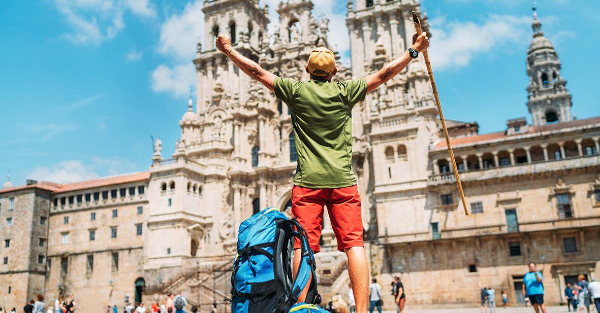 Young backpacker man pilgrim standing with raised arms on the Ob